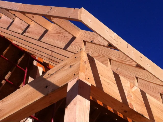 Hip-roof framing corner detail against a deep blue sky on a Hale Development build